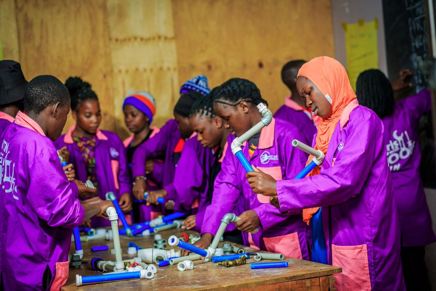 Smart Girls Uganda participants working with piping. 